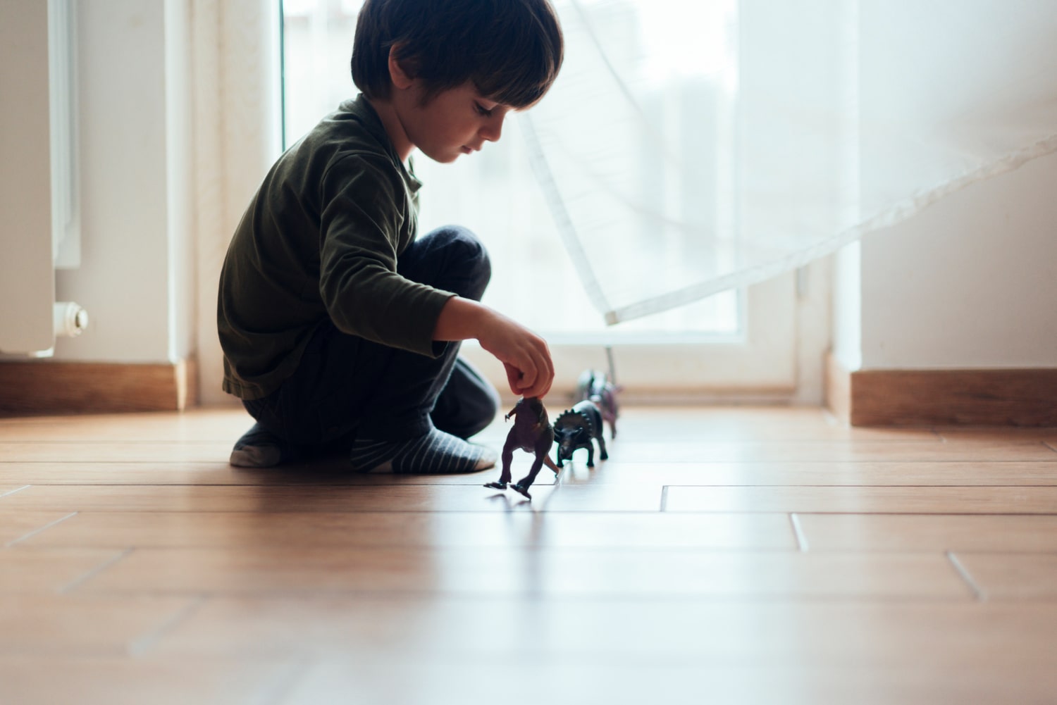 niño con trastorno de conducta jugando en el suelo con dinosaurios de juguete