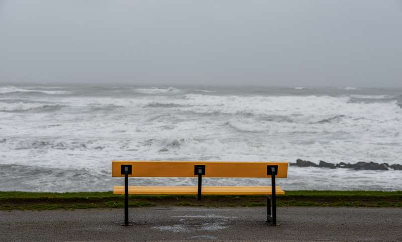 La soledad representada por un banco en la orilla del mar un día nublado